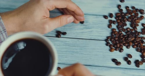 Close Up Coffee Cup With Beans And Hands