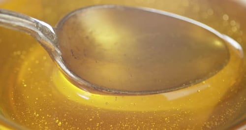 O mel flui de uma colher. Plano de fundo macro.