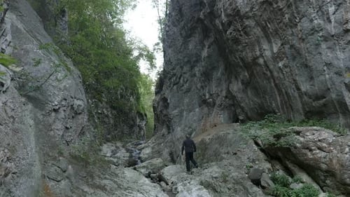 Hiker passing through natural stone bridge 4K 2160p 30fps UltraHD footage - Beauty of nature in Ea