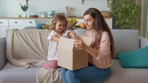 Adorable Girl Unpacking the Order. Happy Mother and Daughter Unpacking the Order.