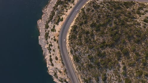 Aerial View From Drone of Cars Going Through Mountain Road Above Rocky Coast
