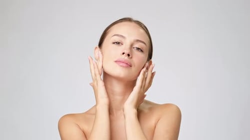 Woman Touches Her Face Gently in Studio Setting