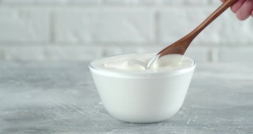 Man's Hand with a Spoon Mixing the Sour Cream in a Bowl