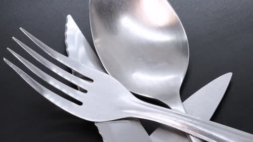 Close up view of steel spoon on a black bacground, rotating motion. Macro shot in 4k.