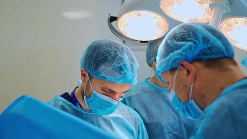 Team surgeon at work in operating room. Group of surgeons at work operating in surgical theatre