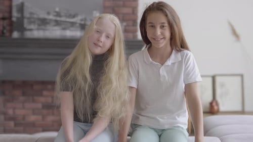 Two Smiling Girls with Long Hair Sitting Together