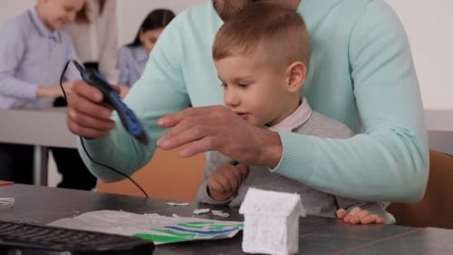 Adult Demonstrates 3D Pen to a Light Haired Child