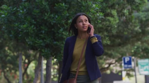 African american woman talking on smartphone while walking in street