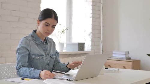 Woman Using Laptop Holding Credit Card Indoors