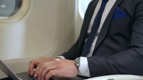 Man Working on Laptop Inside Airplane