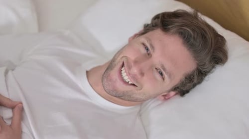 Smiling Man Relaxing in Bed Close Up