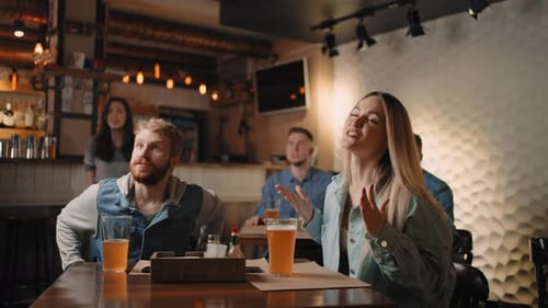 Caucasian Male and Female Friends Cheering Up in Bar Ro Pub When Watching Sport Game