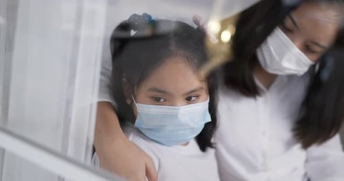 Girl and Adult Wearing Masks Looking Out Window