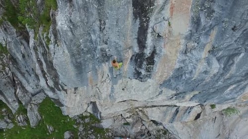 Aerial drone view of a man rock climbing up a mountain.