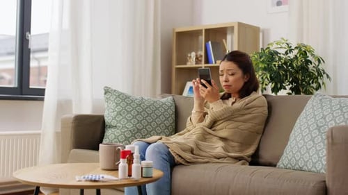 Young Adult with Cold Using Smartphone at Home