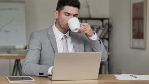 Geschäftsmann trinkt Kaffee und arbeitet am Laptop
