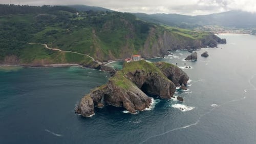 Rippled ocean near green mountain with walkway under sky