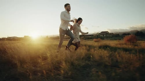 Couple Runs in a Field at Sunset Light