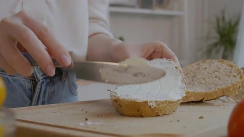 Spreading Cream Cheese on Bread in Kitchen