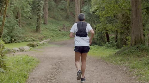 Man in Sportswear Running on Trail in Forest