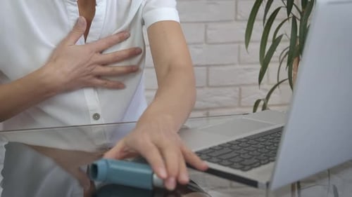 Woman Using Inhaler During Laptop Use at Home