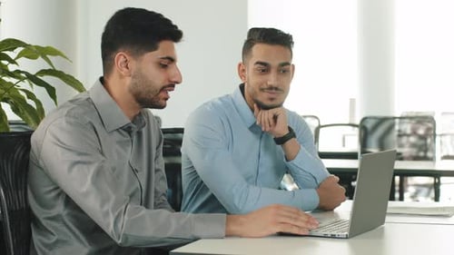 Young Adults Discussing Work at a Laptop