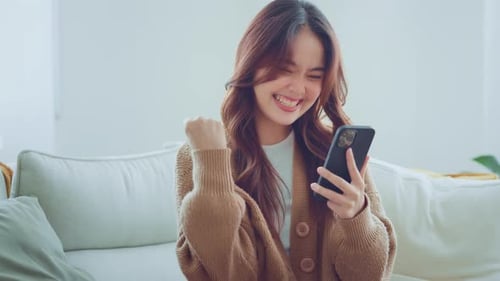 Woman Cheering while Looking at Cellphone