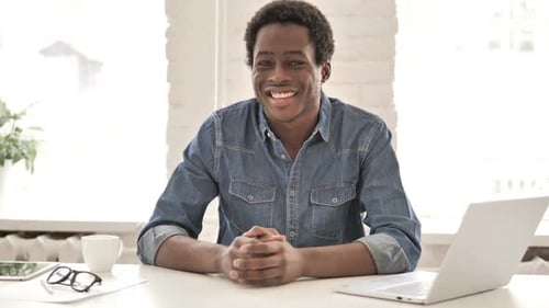 Smiling Man Sitting at Desk with Laptop