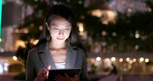 Woman Using Tablet Device in City at Night