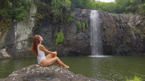 Woman Relaxing by Waterfall in Tropical Setting