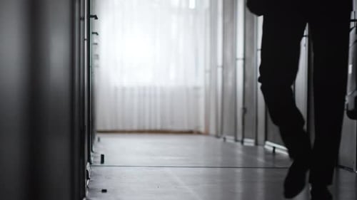 Silhouette Walking Down Institutional Hallway