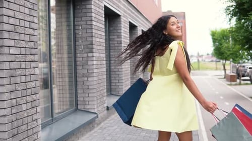 Smiling Woman with Shopping Bags on Urban Sidewalk