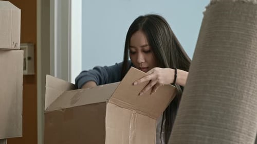 Young Woman Unpacking Moving Boxes with Partner