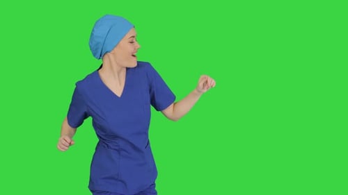 Smiling Female Medical Doctor in Blue Uniform Dancing and Cheering on a Green Screen, Chroma Key