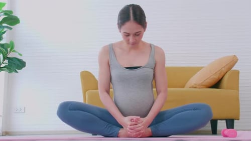 Pregnant Woman Doing Butterfly Yoga Stretch Indoors