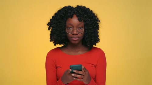 Woman Uses Phone Against Yellow Background