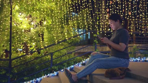 Woman Using Phone on Steps at Night