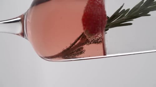 Vídeo vertical, primer plano: una ramita de romero en una copa de champán burbujeante con fresas