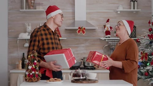 Mature Couple Exchange Christmas Presents in Kitchen