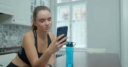 Young Woman Uses Phone After Workout at Home