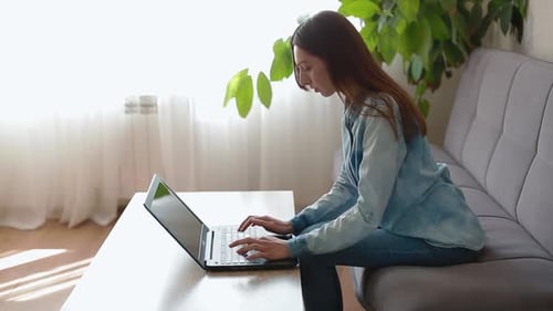 Young Woman Typing on Laptop Computer in Home