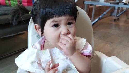 Baby Eating a Red Fruit in High Chair