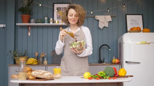 Woman Mixing Salad in Kitchen With Fresh Ingredients