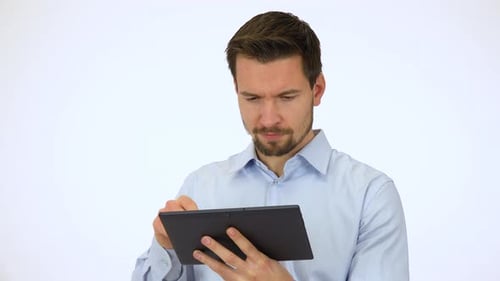 A Young Handsome Man Works on a Tablet, Then Smiles at the Camera - White Screen Studio