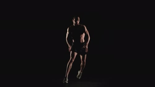 Fit Man Doing Dynamic Exercises on Dark Background