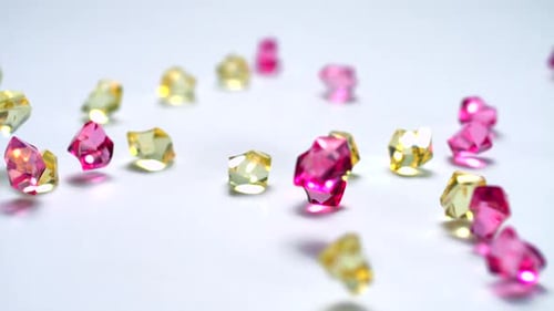 Faceted Pink and Yellow Gemstones Falling on White