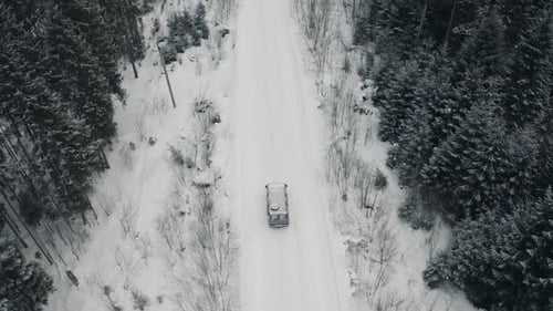 The Car Drives Along the Road in the Winter Forest