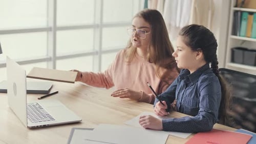 Student Helps Child with Homework at Desk