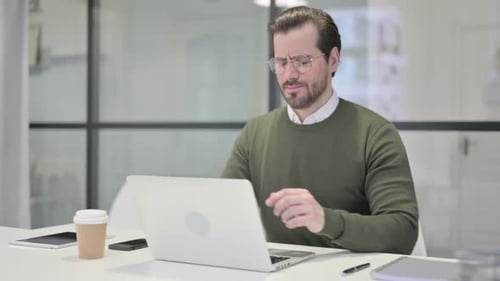 Young Businessman Having Back Pain While Using Laptop in Office