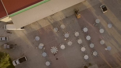 Aerial view of people preparing tables and chairs for a outdoor event in Greece.